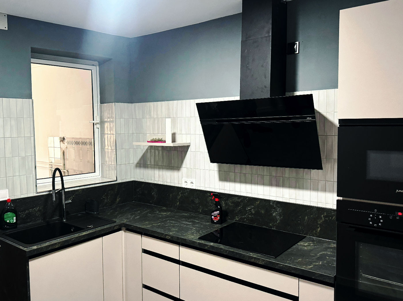 Cocina reformada en el barrio del Cabañal con mobiliario blanco sin tiradores y bancada de silestone oscuro