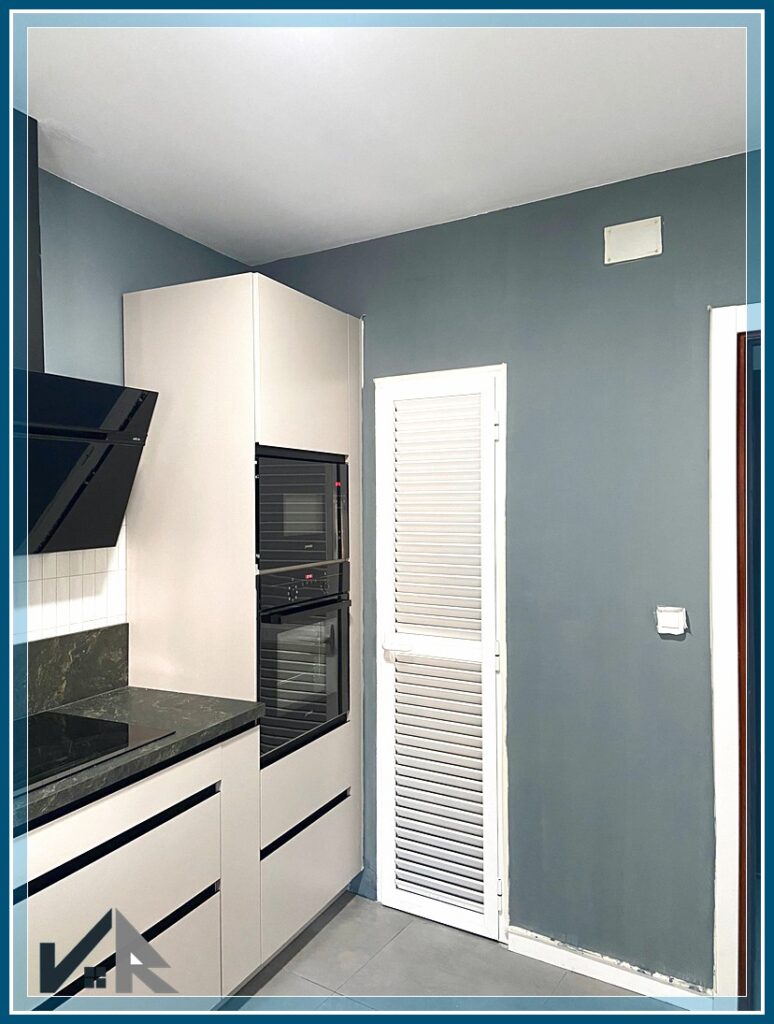 Pared de entrada en la cocina con detalle de puerta de despensa en aluminio con mallorquina