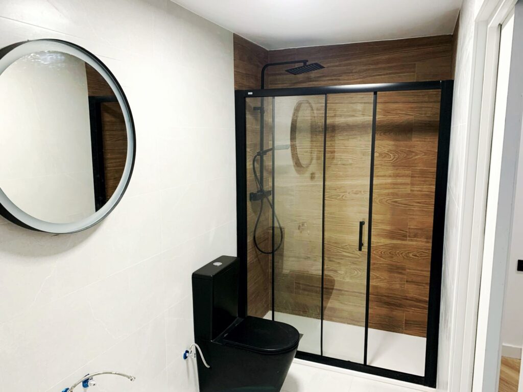 Ducha en apartamento dedicado al alquiler vacacional con diseños en negro y madera