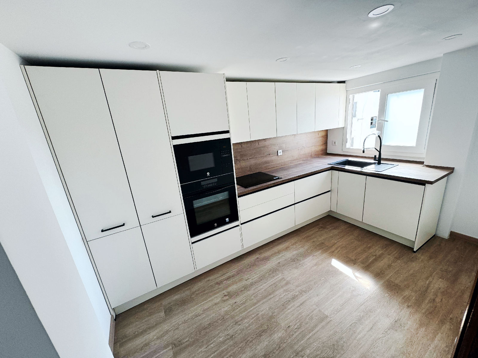 Cocina cuadrada con mobiliario en L en reforma integral de una vivienda realizada en Valencia para clientes de Madrid
