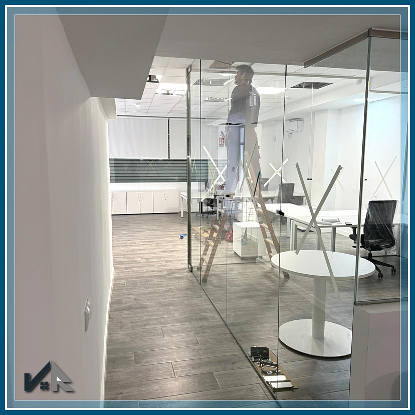Zona de entrada reformada con pavimento vinílico y mamparas de cristal | Office entrance area renovated with vinyl flooring and glass partitions